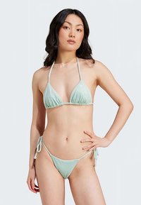 Mintasto zeleni bikini s rebrastom teksturom, trokutastim gornjim dijelom i podesivim vezicama sa strane. Jednostavan dizajn s minimalnim metalnim detaljima za elegantan izgled.