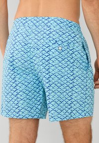 Kupaće šortse u svijetloplavoj boji s tamnoplavim uzorkom valova. Imaju elastičnu traku u struku, bočne džepove i stražnji džep s dugmetom.