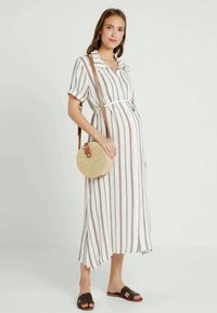 Vestido maxi leve listrado em branco, com listras em bordô, mangas curtas, gola, cintura cingida, combinado com uma bolsa redonda de palha e sandálias rasas.