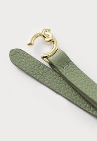 Green textured leather strap with a gold metal clasp. Strap features a smooth finish and a subtle sheen near the clasp.