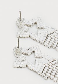 Zilveren stervormige oorbellen gemaakt van kleine metalen vierkanten met een gestructureerd oppervlak, met een post-back sluiting.