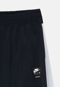 Čierne šortky Nike Air s elastickým pásom a bielym bočným panelom, s logom Nike Air vyšitým pri okraji.