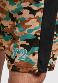 Shorts de camouflage en beige, marron, et turquoise avec une texture en maille. Présente un panneau latéral noir et un audacieux '72' imprimé en bleu clair sur l'ourlet.