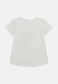 Camiseta blanca de manga corta con cuello redondo, tela suave, dobladillo trasero ligeramente más largo y un diseño simple sin patrones ni gráficos.