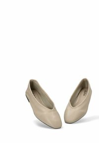 Las bailarinas de cuero beige cuentan con una punta afilada, un tacón bajo y una textura suave con un sutil pespunte. Las plantillas son acolchadas para mayor comodidad.