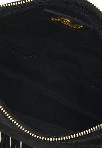 Interno di una borsa in suede nera con zip dorata, dotata di più scomparti e una superficie liscia. Nessun marchio o motivo visibile.