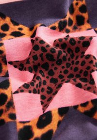 Csillagmintás szövet pink, lila és állatmintás textúrákkal, hangsúlyos fekete és narancssárga leopárdtypekkel.