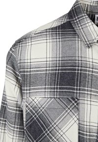 Sort og hvidt ternet flannel skjorte. Har en klassisk krave, brystlomme og et blødt, struktureret stof med kontrasterende mønstre.