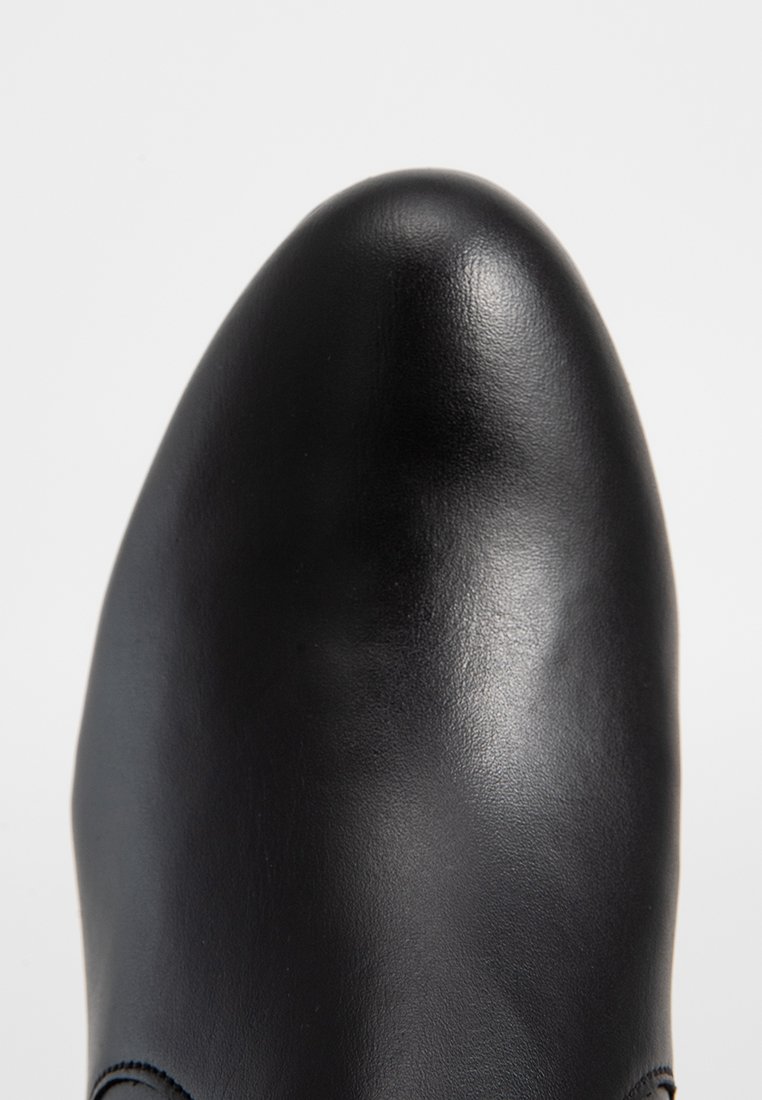 Schwarzer Lederschuh mit polierter Oberfläche, spitzem Zehenbereich und dezenten Nähdetails. Glatte Textur mit schlanker Silhouette.