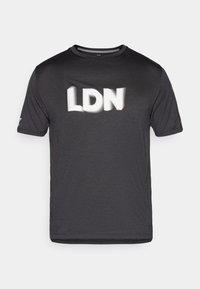 Juodas trumpomis rankovėmis marškinėlių viršus, pagamintas iš tekstūrinės medžiagos, su baltu užrašu "LDN" krūtinėje. Apvalus iškirpimas, minimalus dizainas.