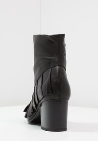 Bottine en cuir noir avec un bout rond, des panneaux latéraux texturés, un talon bloc haut et une finition lisse.