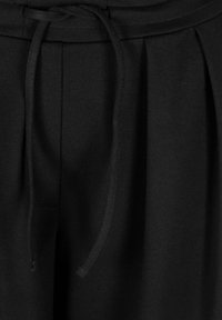 Zwarte broek met een gladde textuur, voorzien van een elastische tailleband met trekkoord en plooien voor ontwerpdetails. De stof is zacht en rekbaar.