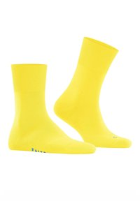 Gelbe knöchellange Socken mit einem gerippten oberen Rand, glatter Textur und kleinem blauen Logodetail nahe der Zehe. Weiche Stoffqualität für zusätzlichen Komfort.