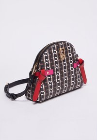 Pieni olkalaukku, jossa on musta ja ruskea kuviollinen pinta, kultavetoketju, koristeellinen kultainen emblem ja punaiset ja vaaleanpunaiset nahkastrapsityylit.