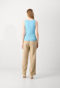Light blue sleeveless top with a smooth texture, paired with beige wide-leg trousers. Shoes feature a thin heel. Back view displayed.