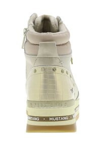 Wysokie trampki w jasnym beżu z błyszczącą panelą o fakturze krokodyla. Posiadają wyściełany kołnierz, metaliczne akcenty oraz wzorzystą podeszwę.