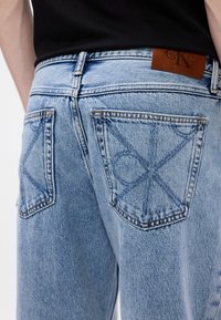 Svetlo modré denimové džínsy s textúrovaným povrchom, s koženou nášivkou Calvin Klein a dvoma zadnými vreckami s X-štýlovým prešívaním.