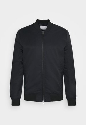 Černá bomber bunda vyrobená z lehkého materiálu, s předním zipem, žebrovanými manžetami a klasickým límečkem. Hladká textura, bez vzorů.