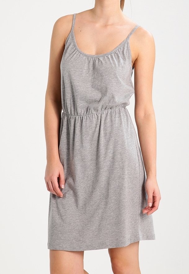 Femme portant une robe sans manches en coton gris clair, longueur genoux, avec de fines bretelles et une taille élastique.