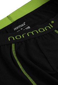 Schwarze Baumwoll-Boxershorts mit einem grünen elastischen Bund, der mit "normani"-Branding und grünen Stichakzenten entlang der Nähte versehen ist.