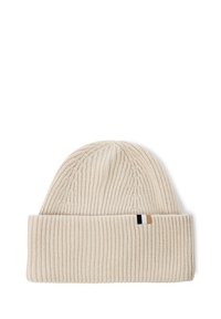 Knit beanie in light beige with a folded cuff. Features a textured rib pattern and a small brand tag in black, white, and tan at the side.