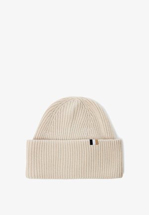 Dzianinowa czapka w jasnym beżu z podwiniętym mankietem. Posiada teksturowany wzór w prążki oraz małą metkę marki w czerni, bieli i beżu po boku.