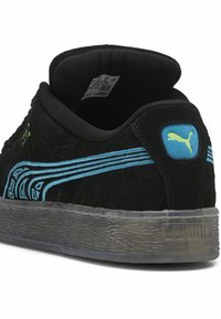 Juodas sportinis batelis su tekstūruotu viršumi, mėlynais akcentais ir skaidriu padu. Ant kulno esantis Puma logotipas ir sudėtingas raštas šonuose.