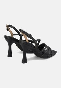 Schwarze High-Heels-Sandalen mit quadratischer Zehenpartie, ausgestattet mit überkreuzten Lederriemen und einem Schnallenverschluss. Strukturierte Fußsohle und Blockabsätze.