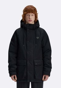 Giacca imbottita nera con cappuccio, chiusura a bottoni a pressione, due tasche frontali e un logo discreto sul petto. Tessuto dalla texture morbida.