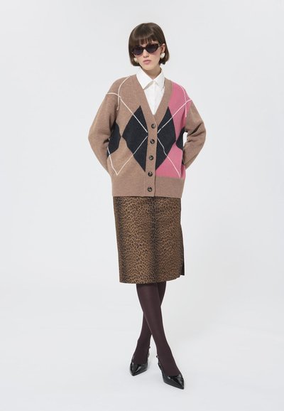 Cardigan cu model maro, cu un design argyle în culorile negru, roz și crem. Fustă cu imprimeu leopard maro. Pantofi negri cu vârf ascuțit, colanți transparenți.