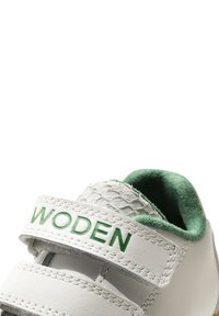 Sneaker bianco con dettagli verdi e una cintura testurizzata, caratterizzato da una soffice foderatura interna verde. Logo stampato sulla cintura. Sistema di chiusura in velcro.