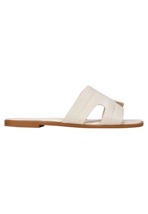Sandales en cuir blanc avec deux larges sangles, une conception à bout ouvert et une semelle beige plate. Présente une couture minimaliste pour le détail.