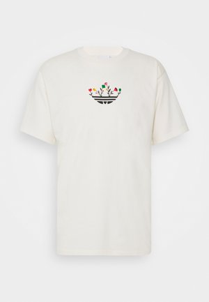 Kortærmet, cremefarvet bomulds-T-shirt med blomsterdesign i rød, gul og grøn over en sort grafik på en rund halsudskæring.