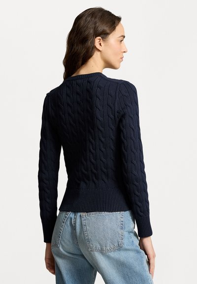 Navy cable-knit sweater with ribbed hem and cuffs, featuring woven texture. Back view shows the fitted design and crew neckline.