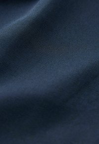 Tissu bleu marine avec une texture lisse, présentant un motif à rainures subtiles, mettant en valeur des tissages fins et réguliers sans défauts visibles.