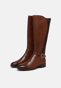 Brown leather knee-high boots with a textured black fabric panel and a silver hardware accent on the ankle strap. Smooth finish, sleek design.