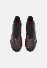 Černé sportovní boty s červenými a šedými akcenty, s elegantním, štíhlým designem, texturovaným svrškem a konstrukcí na nazouvání.