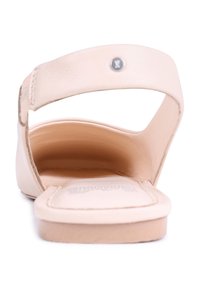 Sandalias de cuero beige con la punta abierta y una correa ancha en el pie, que cuentan con una plantilla texturizada y un diseño suave y minimalista.