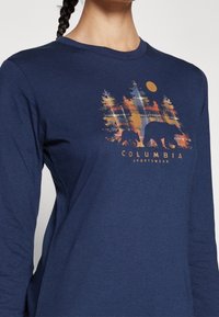 Navy Langarmshirt mit einem bunten Bären- und Waldgrafik sowie dem Text "Columbia Sportswear" darunter. Weicher, strukturiertes Material.