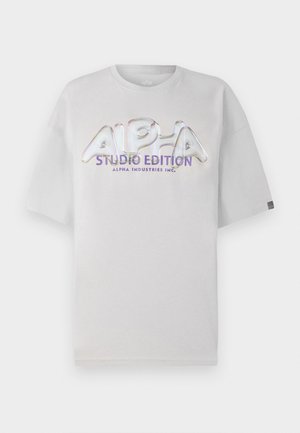Weißes kurzärmliges T-Shirt mit Rundhalsausschnitt, auf dessen Vorderseite ein glänzendes, mehrfarbiges "ALPHA STUDIO EDITION" Logo prangt.