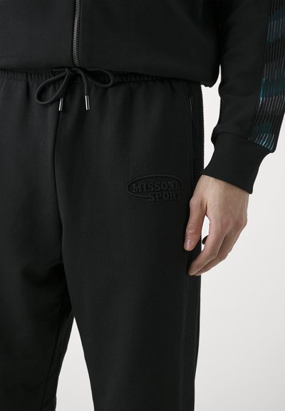 Black sports joggers with an elastic waistband and drawstring. Features textured side panels and a raised "MISSONI SPORT" logo on the thigh.