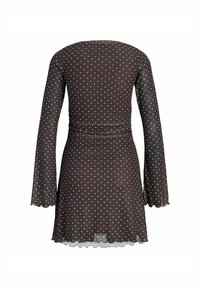 Vestido negro de manga larga con lunares blancos, cintura ajustada, y ligero volante en los puños y el dobladillo, visto desde la parte posterior.