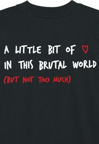 Black t-shirt featuring bold, multi-colored text: "A little bit of ❤️ in this brutal world (but not too much)." Soft cotton material.