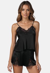 Ensemble de camisole et de short en satin noir avec un décolleté à bord en dentelle, des bretelles réglables et des fentes sur les côtés du short pour un ajustement décontracté.