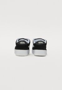 Fekete velúr Vans sportcipők fehér гумírozott talppal, párnázott szegéllyel és sarokkal, hátsó részén dombornyomott logóval.