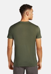 Camiseta de manga corta para hombre en verde oliva. Tela lisa y texturizada con un cuello redondo y un corte relajado. Sin detalles o acentos prominentes.