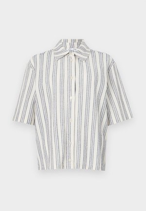 Kreklu ar īsām piedurknēm, kas izgatavots no krēmkrāsas auduma ar tumši zilu vertikālu svītru rakstu. Izgatavots no viegla materiāla, ar standarta apkakli un brīvu piegriezumu.