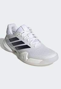 Biela športová obuv s textúrovaným zvrškom, tromi čiernymi pruhmi a ľahkou podrážkou s priehľadným detailom.