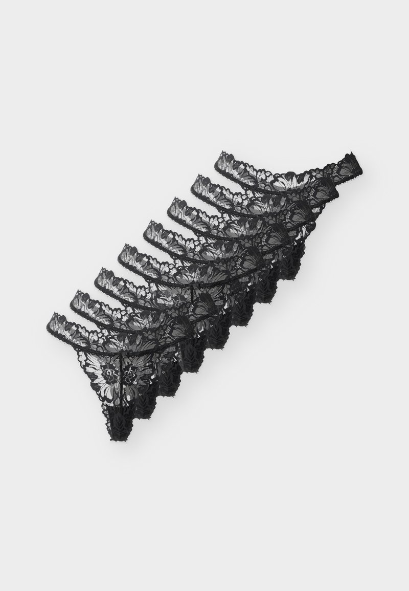 Επτά μαύρα γυναικεία εσώρουχα-στρινγκ από δαντέλα, τοποθετημένα διαγώνια σε λευκό φόντο.