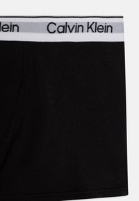 Mustad puuvillased poksijad, millel on valge ja hall elastne vöökoht, millel on "Calvin Klein" tekst. Sile tekstuur, sobiv kuju.
